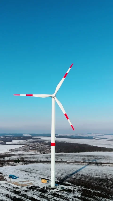 Wind turbine with red and white blades rotates against a clear blue sky Stock Footage 347360892
