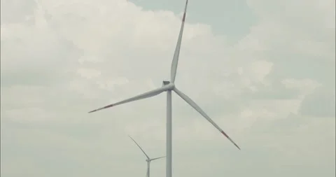 Wind turbine rotating blades generating green energy under cloudy sky Stock Footage 304299746