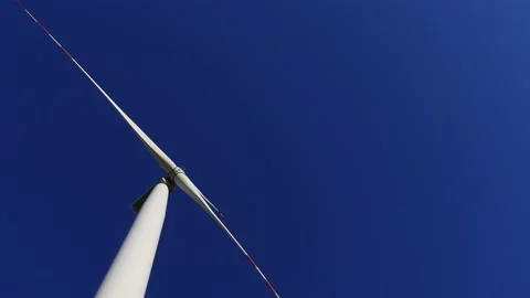 Wind turbine rotating slowly in the background of deep blue sky. Video stock 219997998