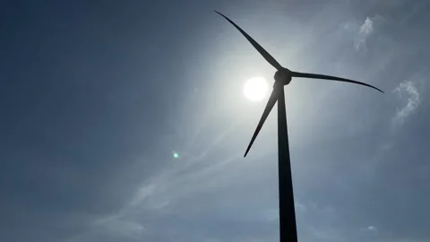 A wind turbine seen from below rotates steadily, its silhouette standing out Stockbeeldmateriaal 333981732