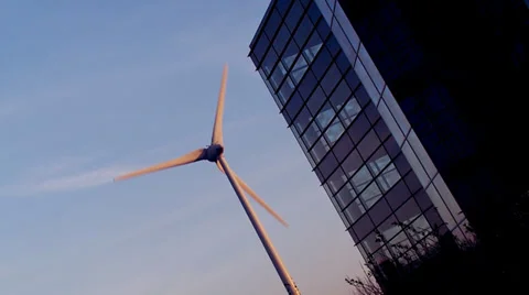 Wind turbine set against the side of a modern generic office building providing Vídeos de archivo 32961641