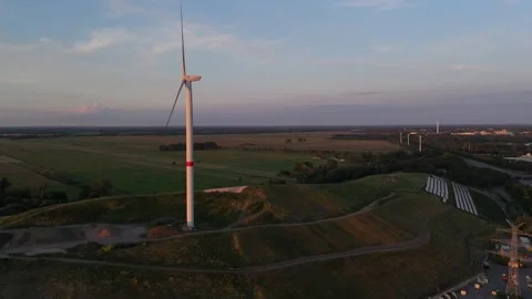 Wind Turbine side view above a Solar Farm at Dusk Aerial View 動画素材 337850466