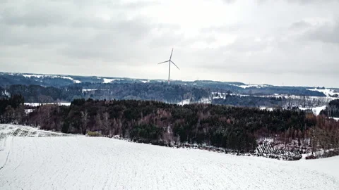 Wind turbine spinning in front of forest in winter Stock Footage 147320510