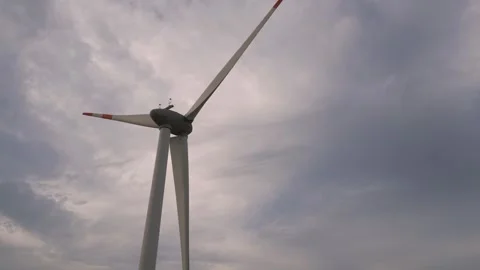 Wind turbine spinning under cloudy sky in rural area Video stock 309425991