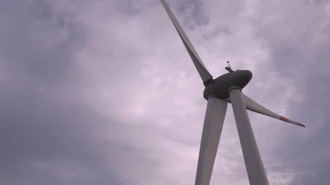Wind turbine spins under cloudy sky in renewable energy demonstration Stock Footage 308247103