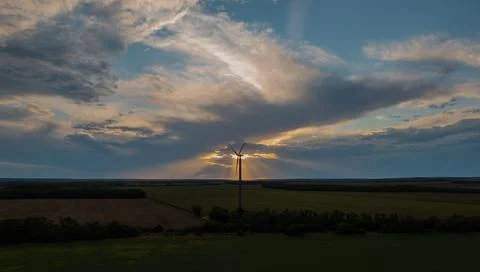 Wind Turbine at Sunset with Dramatic Sky Over Fields Stock Photos