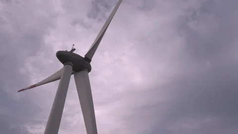 Wind turbine technician performs maintenance on large turbine in cloudy weather Video stock 308247090