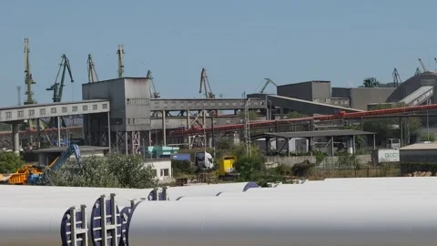 Wind turbine tower components stored at industrial port Stock Footage 345928278