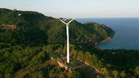 Wind turbine towering over hill with stunning ocean view. Large wind turbine Stock Footage 240151263