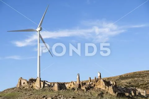 Wind turbine towering over old farmhouse ruin Stock Photos