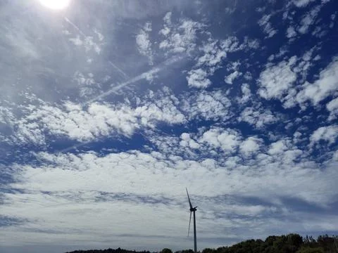 Wind turbine under dramatic cloudy blue sky Stock Photos