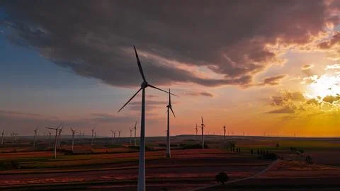 Wind turbine under orange cloud edges at sunset. A white tower stands again.. Stock Photos
