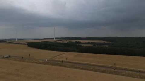 Wind turbines above harvested fields under heavy grey clouds 스톡 동영상 340367940