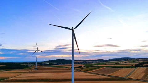 Wind turbines above patchwork farmland under pale evening sky Stock Footage 339748602