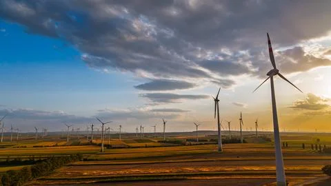 Wind turbines across fields beneath an overhanging cloud. A tower fills the.. Stock Photos