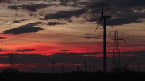 Wind turbines and burning red sky with pylon in the background Stockbeeldmateriaal 70716161