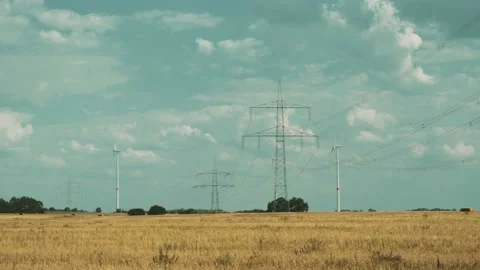 Wind turbines and high voltage towers with wires on barren field 스톡 동영상 203904732