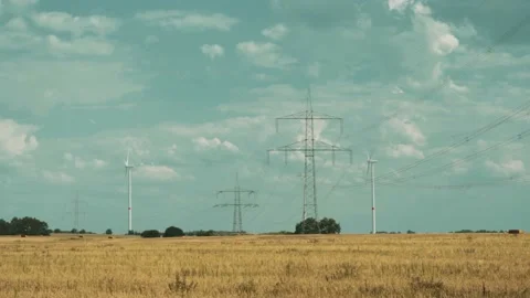 Wind turbines and high voltage towers with wires on barren field 스톡 동영상 203904740