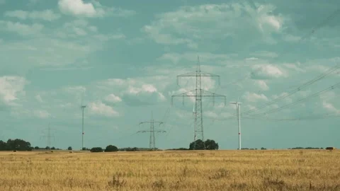 Wind turbines and high voltage towers with wires on barren field 스톡 동영상 203904748