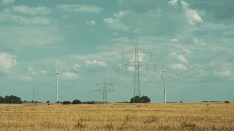 Wind turbines and high voltage towers with wires on barren field 스톡 동영상 203904749