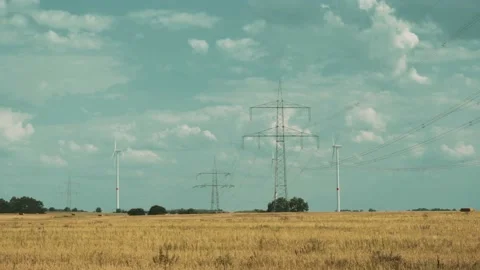 Wind turbines and high voltage towers with wires on barren field 스톡 동영상 203904753
