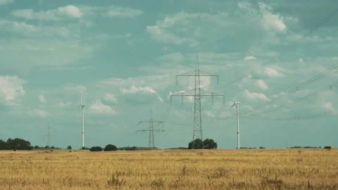 Wind turbines and high voltage towers with wires on barren field 스톡 동영상 203904826