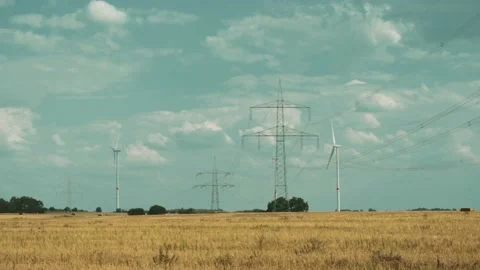 Wind turbines and high voltage towers with wires on barren field 스톡 동영상 203904827
