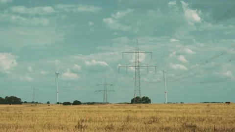 Wind turbines and high voltage towers with wires on barren field 스톡 동영상 203904830