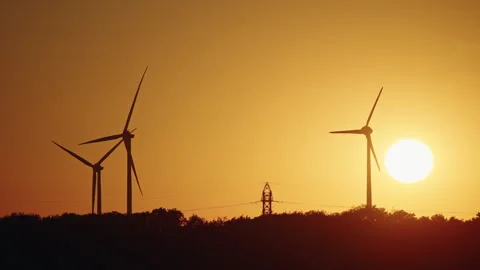 Wind Turbines and Power Lines Silhouetted at Sunset Stock Footage 344563625