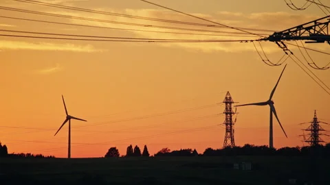 Wind Turbines and Power Lines Silhouetted at Sunset Stock Footage 344563908