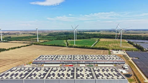 Wind turbines and solar panels seen near a large building in the countryside Vidéo 342714731