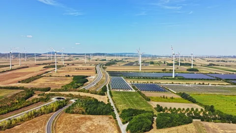 Wind turbines and solar panels in a rural landscape with fields and roadways Stock Footage 342745471