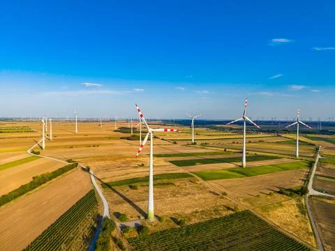 Wind turbines are placed in open fields showing different types of crops. The Stock-Fotos