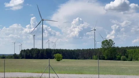 Wind turbines on the background of a blue sky and green field, natural energy. Stock Footage 287622796