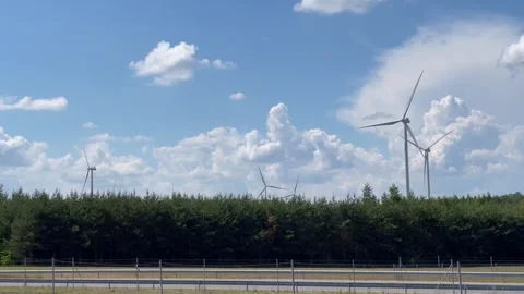 Wind turbines on the background of a blue sky and green field, natural energy. Stock Footage 287622936