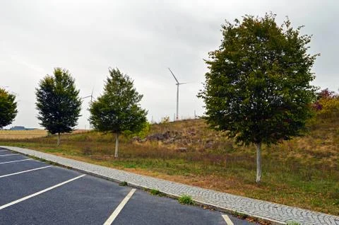 Wind turbines between trees on the background of the cloudy sky Stock Photos