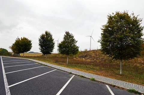 Wind turbines between trees on the background of the cloudy sky Stock Photos