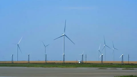 Wind turbines with blades for generating electricity among a yellow field Stock Footage 163742017