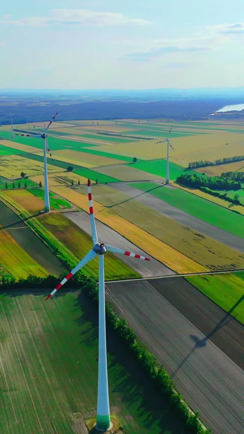 Wind turbines casting shadows across farmland. Vertical video. Stock Footage 321887513