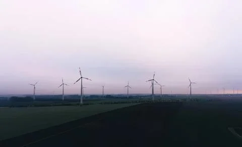 Wind turbines on a cloudy sky in a flat landscape Stock Photos