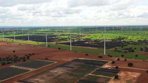 Wind Turbines Dance in Harmony Over Vast Green Fields and Solar Farms Stock Footage 341902254