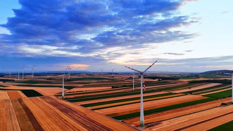 Wind turbines distributed across striped farmland beneath blue clouds Stockbeeldmateriaal 339746911