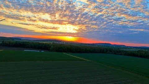 Wind Turbines at Dramatic Golden Sunset Over Green Fields Stock Photos