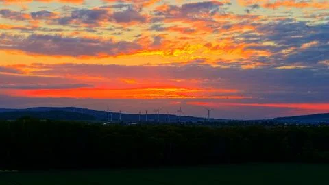 Wind Turbines at Dramatic Golden Sunset Over Green Fields Fotos Stock