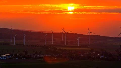 Wind Turbines at Dramatic Orange Sunset Over Rural Landscape Foto stock