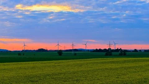 Wind Turbines at Dramatic Sunset Over Green Fields Foto stock