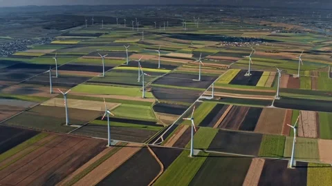 Wind turbines generate clean energy across vibrant farmland 動画素材 320304510