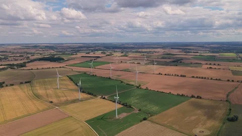 Wind Turbines Generate Clean Energy Across Vast Yellow Farm Fields During a Stock Footage 341838067