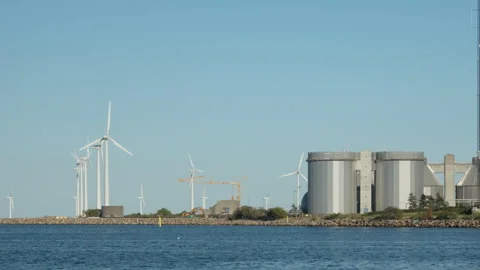 Wind turbines generate renewable energy along industrial harbor in Copenhagen Stock Footage 344745255