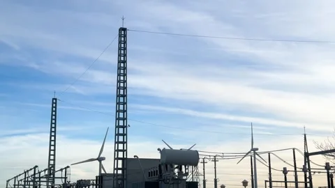 Wind turbines generating clean electricity at a power substation Stock Footage 326790345